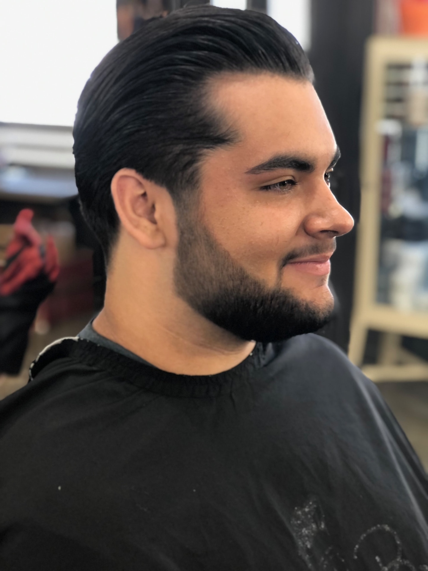 Slicked-back hairstyle and shaped beard by Ruben